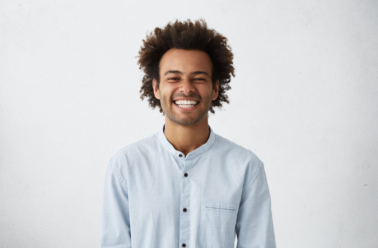 A person smiles at the camera, showing off their full rows of teeth.