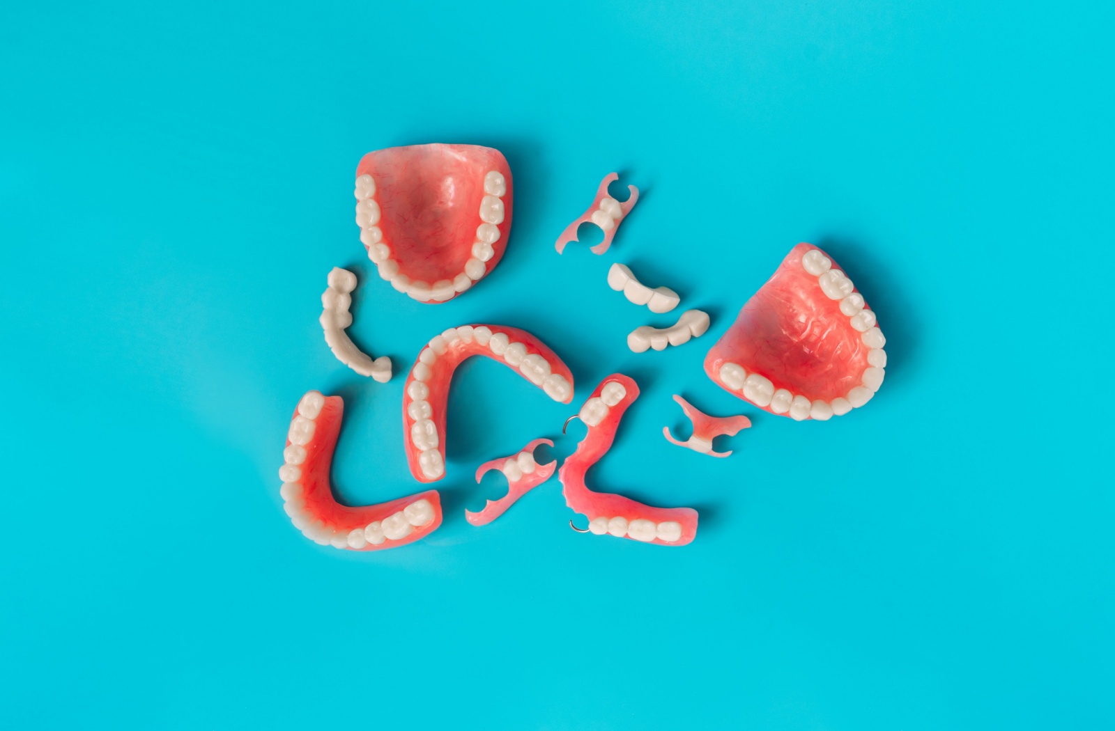 A variety of dentures resting against a bold, blue background.