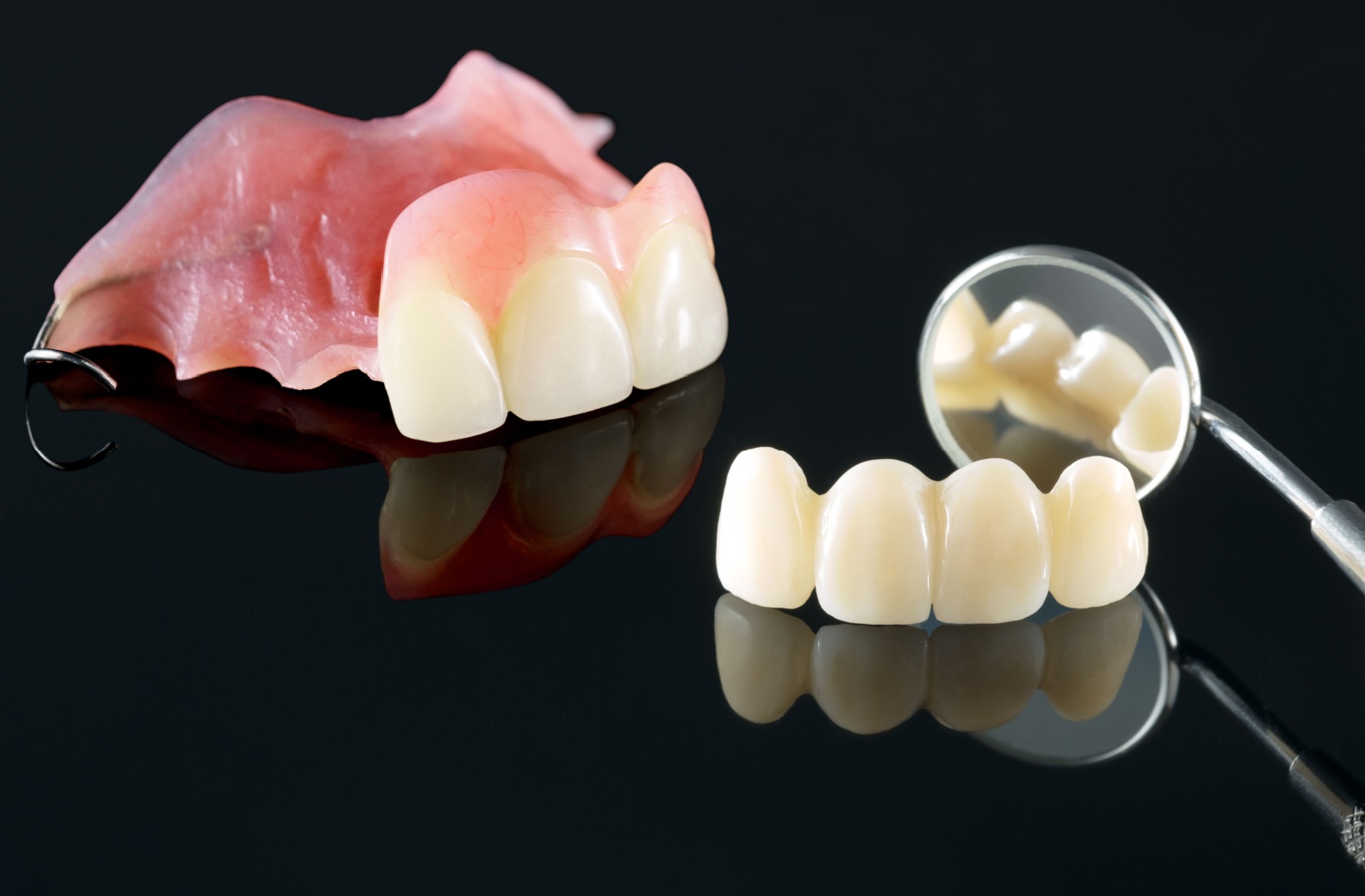 Partial dentures for front teeth resting against a black surface.