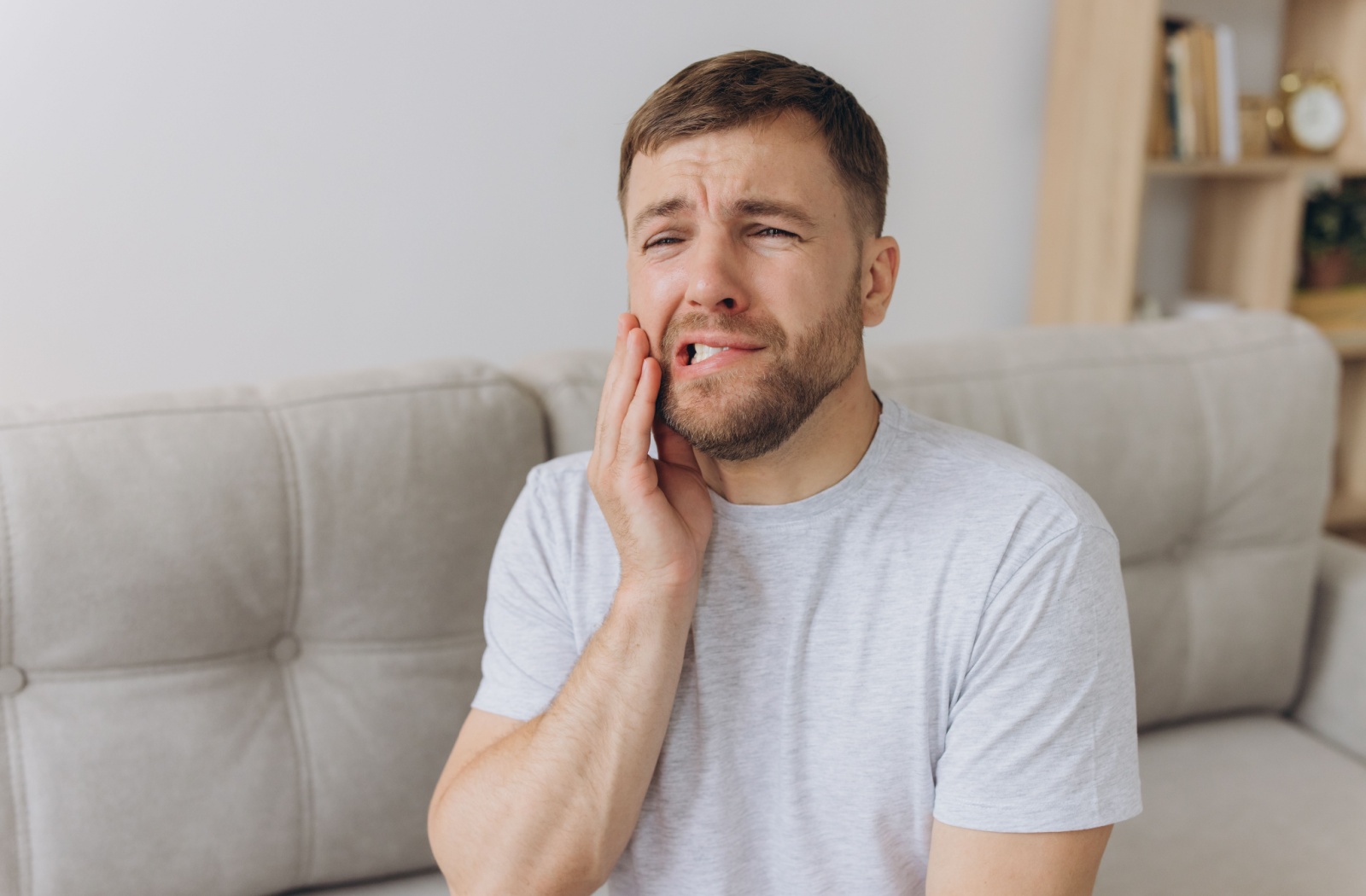 A man holding his mouth due to discomfort in his tooth.