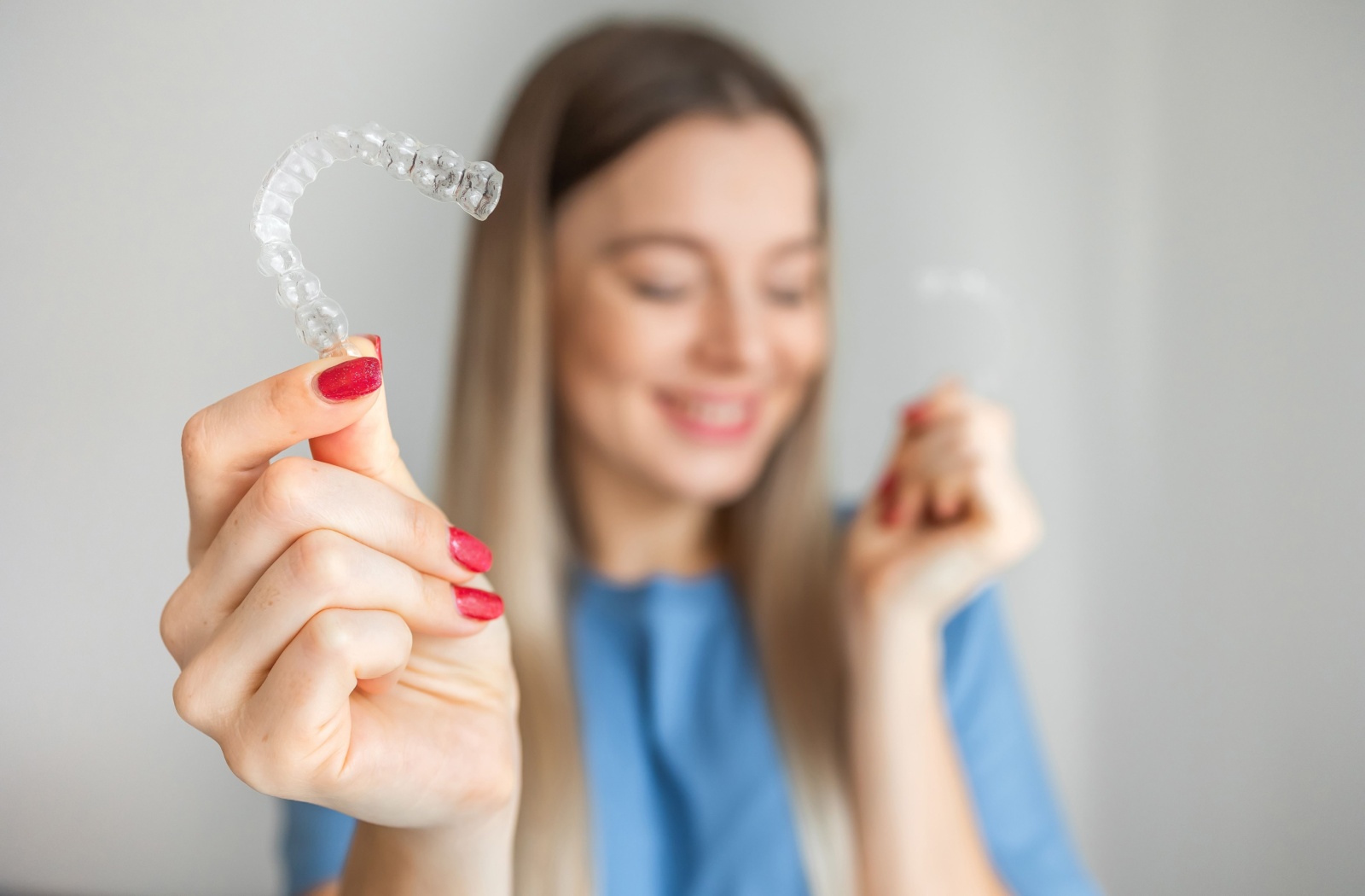 Woman smiling and holding up her Invisalign