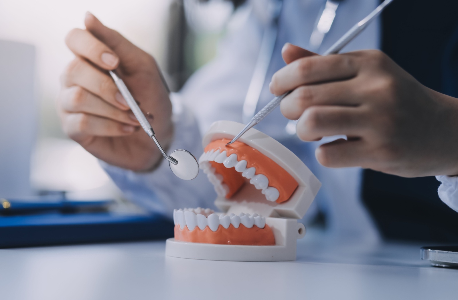 Mock up of dentures with dentists hands showing how they function with dental tools.