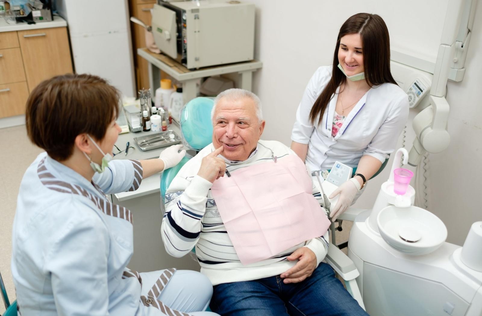 Patient speaking with a dental team about denture care during a dental appointment.